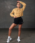 Model in LYFTLYFE yellow cropped hoodie and black shorts, shown full length.
