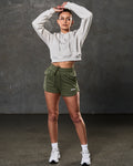 Full outfit view with fleece crop hoodie in sand and green workout shorts.