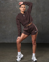 Model in LYFTLYFE brown cropped hoodie and shorts, shown full length.