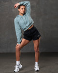 Full body shot of slate cropped hoodie paired with black athletic shorts.