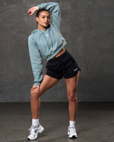 Full body shot of slate cropped hoodie paired with black athletic shorts.