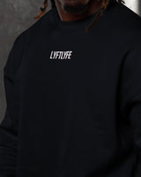 Zoomed-in view of men’s black fleece crewneck showcasing ribbed hem and high-quality Lyftlyfe branding detail.