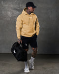 Full-body shot of man in LYFTLYFE yellow hoodie and black shorts.