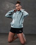 Lifestyle shot of women’s hoodie in slate color styled with black athletic shorts.