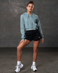 Full body shot of cropped hoodie in slate color paired with black athletic shorts.