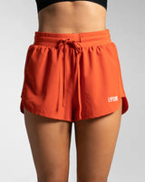 High-waisted cherry red women's HIIT shorts with front drawstrings and LYFTLYFE logo.
