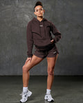 Head-to-toe fit showing elite hoodie in brown and matching color shorts.
