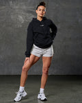 Head-to-toe fit showing women's elite hoodie in black and light grey shorts.