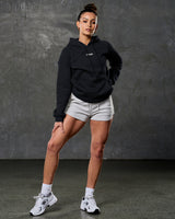 Head-to-toe fit showing women's elite hoodie in black and light grey shorts.