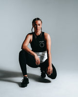 Women’s sleeveless shirt with two panels, black on top and white at the bottom, made with tri-blend fabric for performance and sweat-wicking.