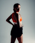 Athletic woman in LYFTLYFE cherry red sports bra and black HIIT shorts posing confidently in studio lighting.
