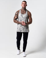 Full body shot of model in grey gym stringer and black joggers.