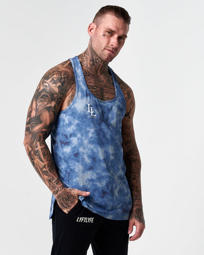 Blue tie dye racerback tank top with white LL logo on a light grey background.