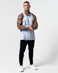 Head-to-toe shot of model wearing blue marble gym tank with black joggers.