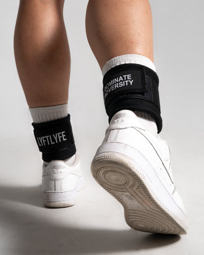 Walking motion wearing LYFTLYFE ankle straps in black, visible branding on both sides of durable neoprene material.