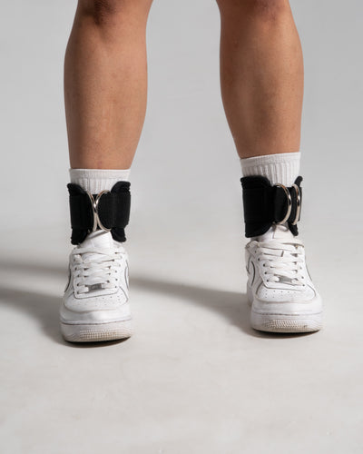 Walking motion wearing LYFTLYFE ankle straps in black, visible branding on both sides of durable neoprene material.