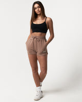 Front view of women’s high-waisted Balance Shorts in taupe featuring an elasticized waistband, drawstring, and side pockets.