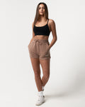 Front view of women’s high-waisted taupe Balance Shorts featuring an elasticized waistband, drawstring, and side pockets.