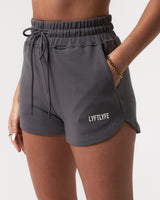 Close-up of women’s Balance Shorts in dark grey, featuring the white Lyftlyfe logo, elasticized waistband, and tonal drawstring.