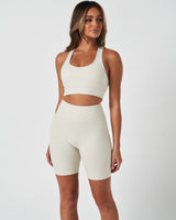 Front shot of woman in LYFTLYFE Force shorts and bra set in vapor white, styled for high-performance workouts.