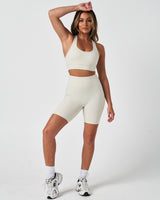 Model wearing vapor white LYFTLYFE 6.5'' biker shorts and matching sports bra in a full-length activewear look.