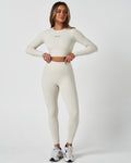 Full-length outfit view showing sculpted leggings paired with matching long sleeve top in light beige.