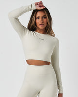 Women’s long sleeve workout crop top in white, featuring compressive fit and soft 4-way stretch fabric.