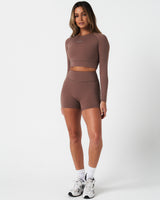 Full body shot of brown Force Crop top, styled with high-waisted shorts for a sleek gym outfit.