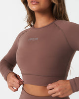 Detailed view of minimalist Lyftlyfe logo printed on brown women’s long sleeve crop top.