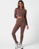 Full body shot of model in Force leggings and matching long sleeve crop top in brown, highlighting full fit.