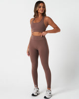 Full body shot of model in Force leggings and matching top in brown, highlighting full fit.