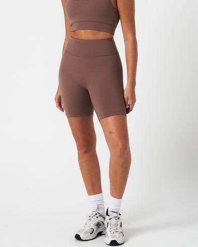 Women’s brown high-waisted performance shorts with compressive fit and seamless design, shown from the front.