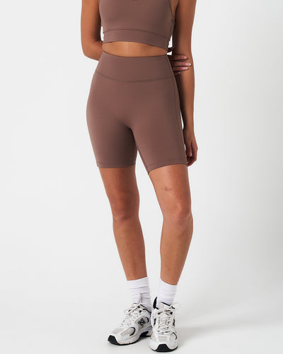 Women’s brown high-waisted performance shorts with compressive fit and seamless design, shown from the front.