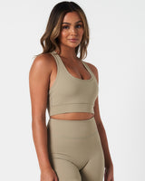 Women’s supportive sports bra in light green, highlighted from the right side to show sculpted shaping.