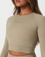 Detailed view of minimalist Lyftlyfe logo printed on light green women’s long sleeve crop top.