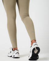 Detailed view of LYFTLYFE reflective logos near ankle cuffs on Force leggings in light green.