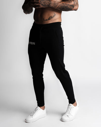Men’s black joggers left side view showing zipper pocket and slim leg fit.