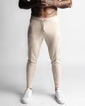 Front view of Function joggers in beige color with LYFTLYFE logo and tapered fit. 