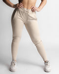 Woman wearing beige joggers, standing pose showing full tapered fit. 