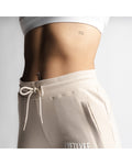 Detailed view of women's joggers in beige with elastic waistband and secure pocket. 