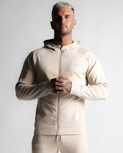 Men's hoodie in sand color side angle with LYFTLYFE logo and full zip design.