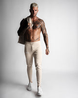 Front angle of athletic beige joggers with minimalist design and logo. 