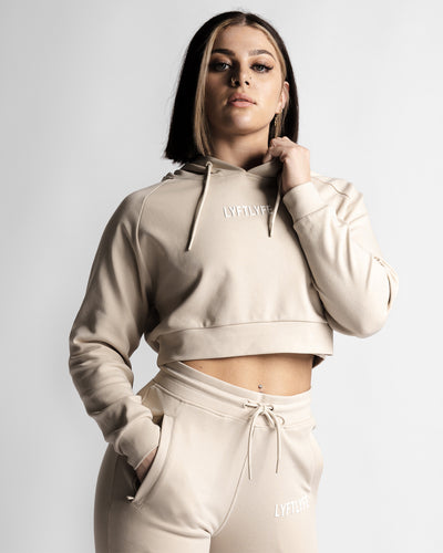 Cropped front view of LYFTLYFE React hoodie in beige showing logo and high-waist jogger pairing.