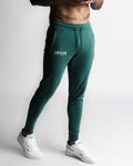 Left side view of men’s Function joggers in dark green with hidden zipper pocket detail. 