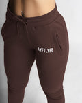 Close-up of dark brown joggers waistband with tonal drawstrings and soft fabric. 