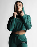 Woman modeling hooded LYFTLYFE crop hoodie in green with confident look.