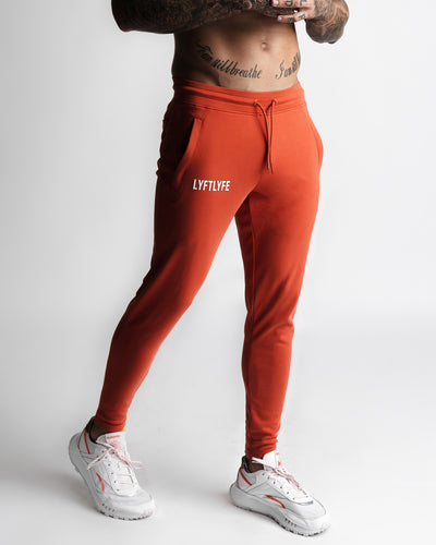 Cherry red sweatpants with a white LYFTLYFE logo on a gray background