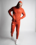 Full-body athletic look in Function hoodie with hood on and joggers in red. 