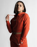 Woman in side pose wearing red React crop hoodie and high-rise joggers. 