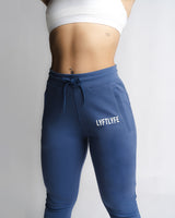 Close-up of LYFTLYFE branding and front pocket detail on high-waisted joggers in blue.